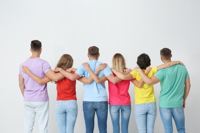 Photo of Group of young people hugging each other on light background. Unity concept