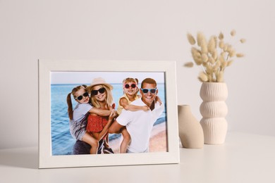 Frame with family photo and other decor elements on white table