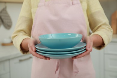 Photo of Woman holding plates in kitchen, closeup view