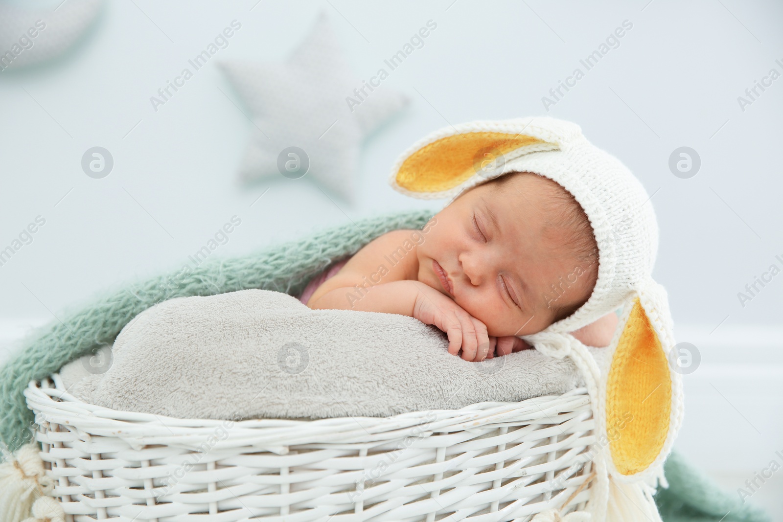 Photo of Adorable newborn child wearing bunny ears hat in baby nest indoors