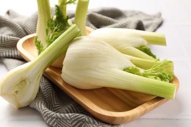 Whole and cut fennel bulbs on white table, closeup