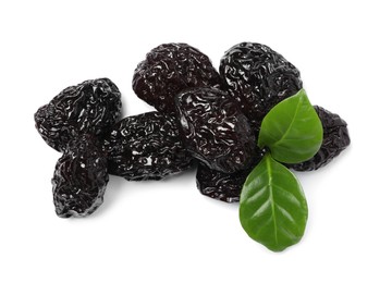 Heap of sweet dried prunes and green leaves on white background