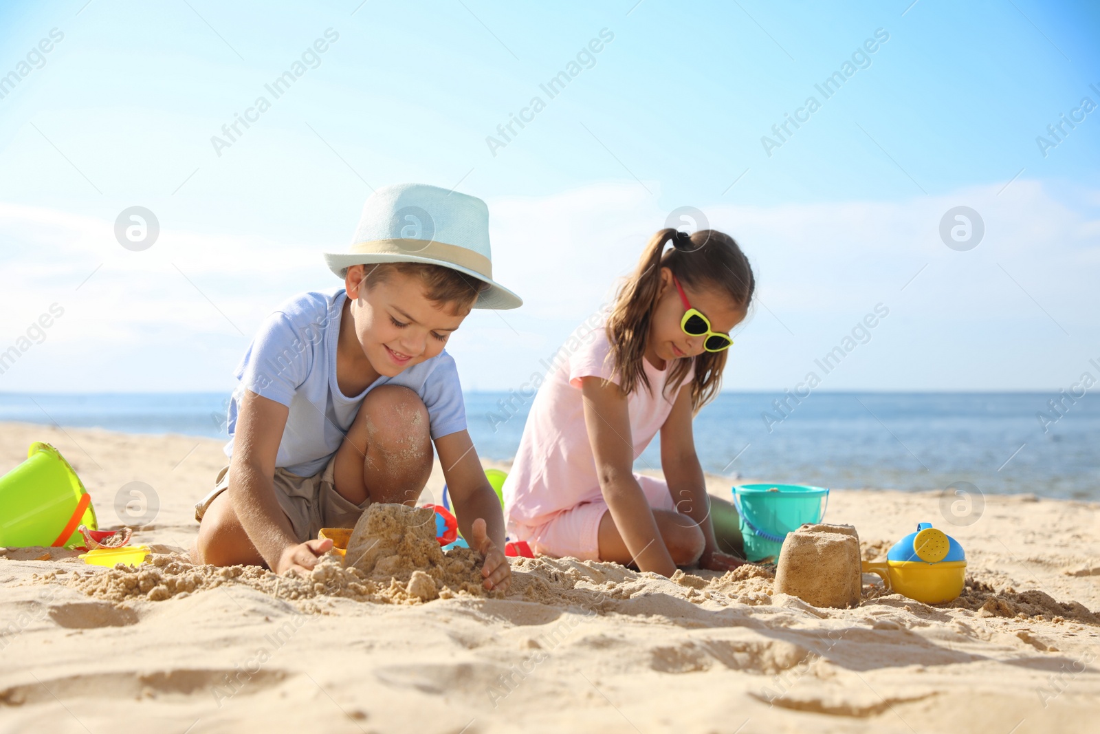 Photo of Cute little children playing with plastic toys on sandy beach