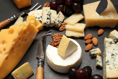 Photo of Composition with different sorts of cheese and knives on black table, closeup