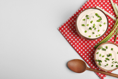 Photo of Fresh sour cream with onion on white table, flat lay. Space for text