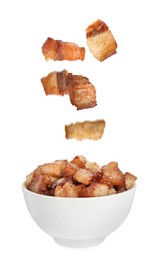 Image of Tasty fried cracklings falling into bowl on white background. Cooked pork lard