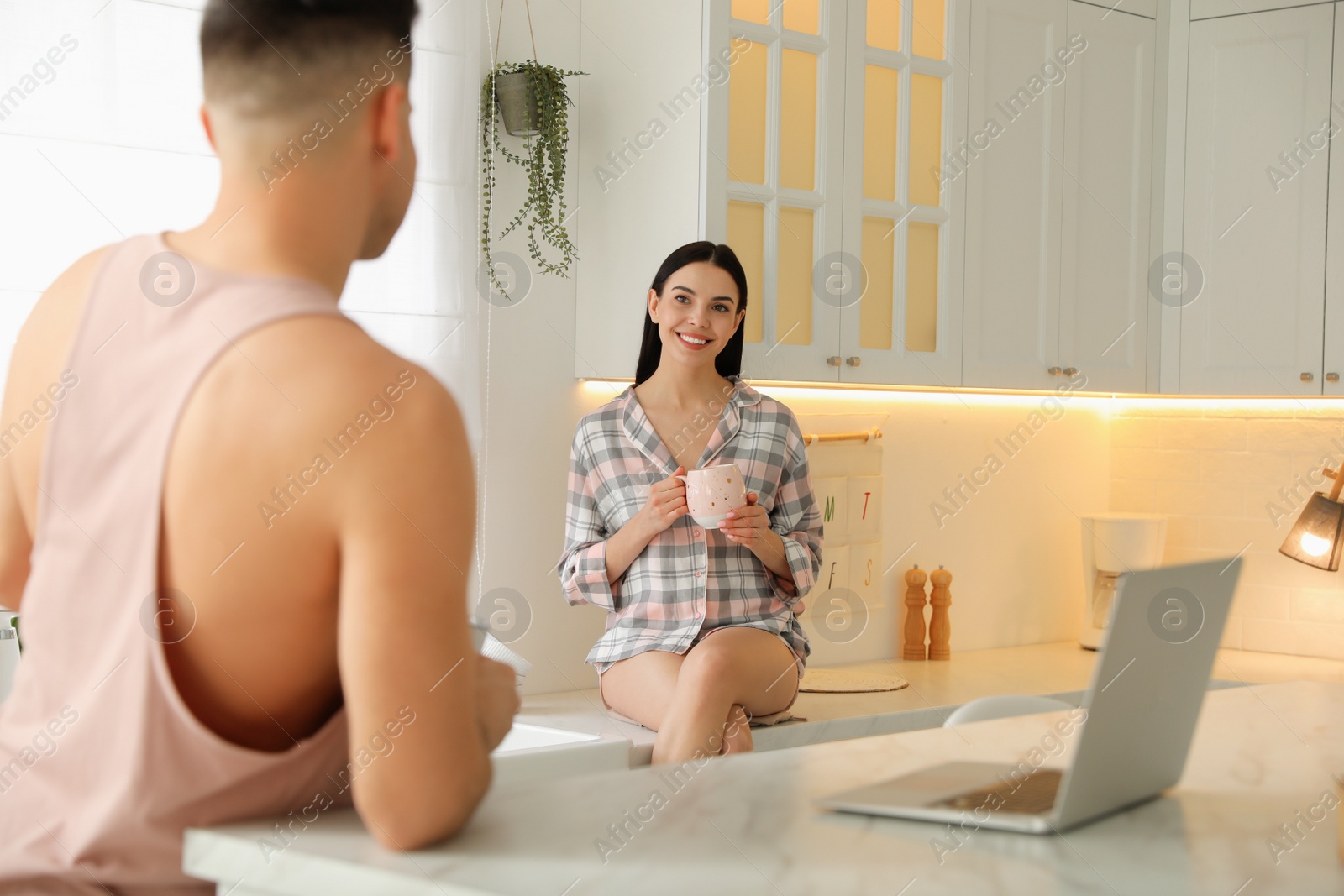 Photo of Happy couple wearing pyjamas and spending time together in kitchen