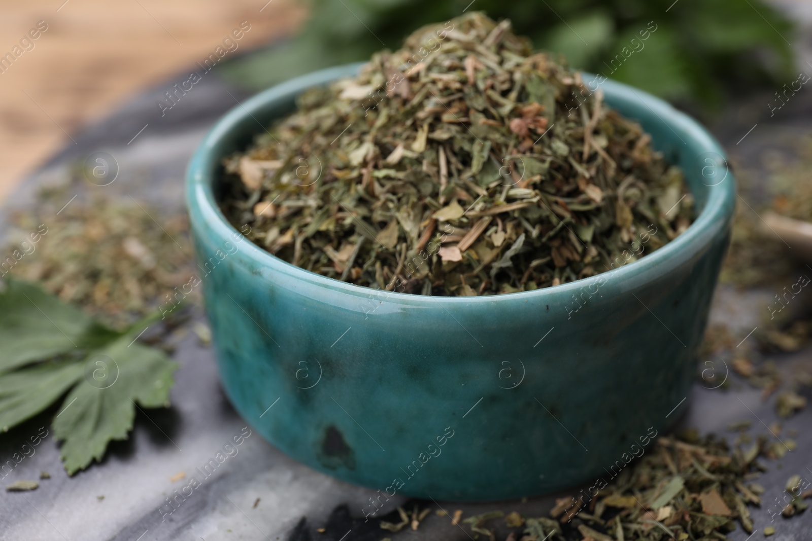 Photo of Dried parsley in bowl on table, closeup