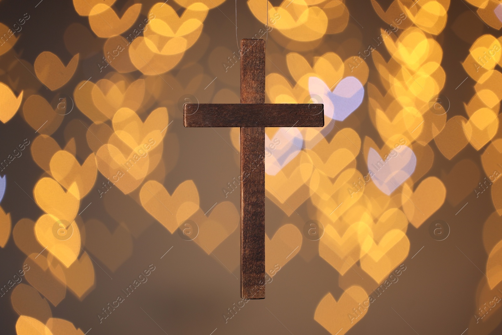 Photo of Wooden cross against blurred lights, closeup. Religion of Christianity