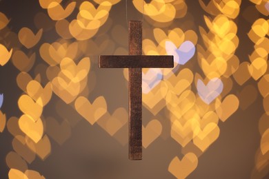 Photo of Wooden cross against blurred lights, closeup. Religion of Christianity