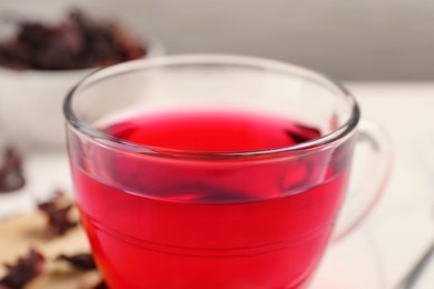 Cup of fresh hibiscus tea on table, closeup