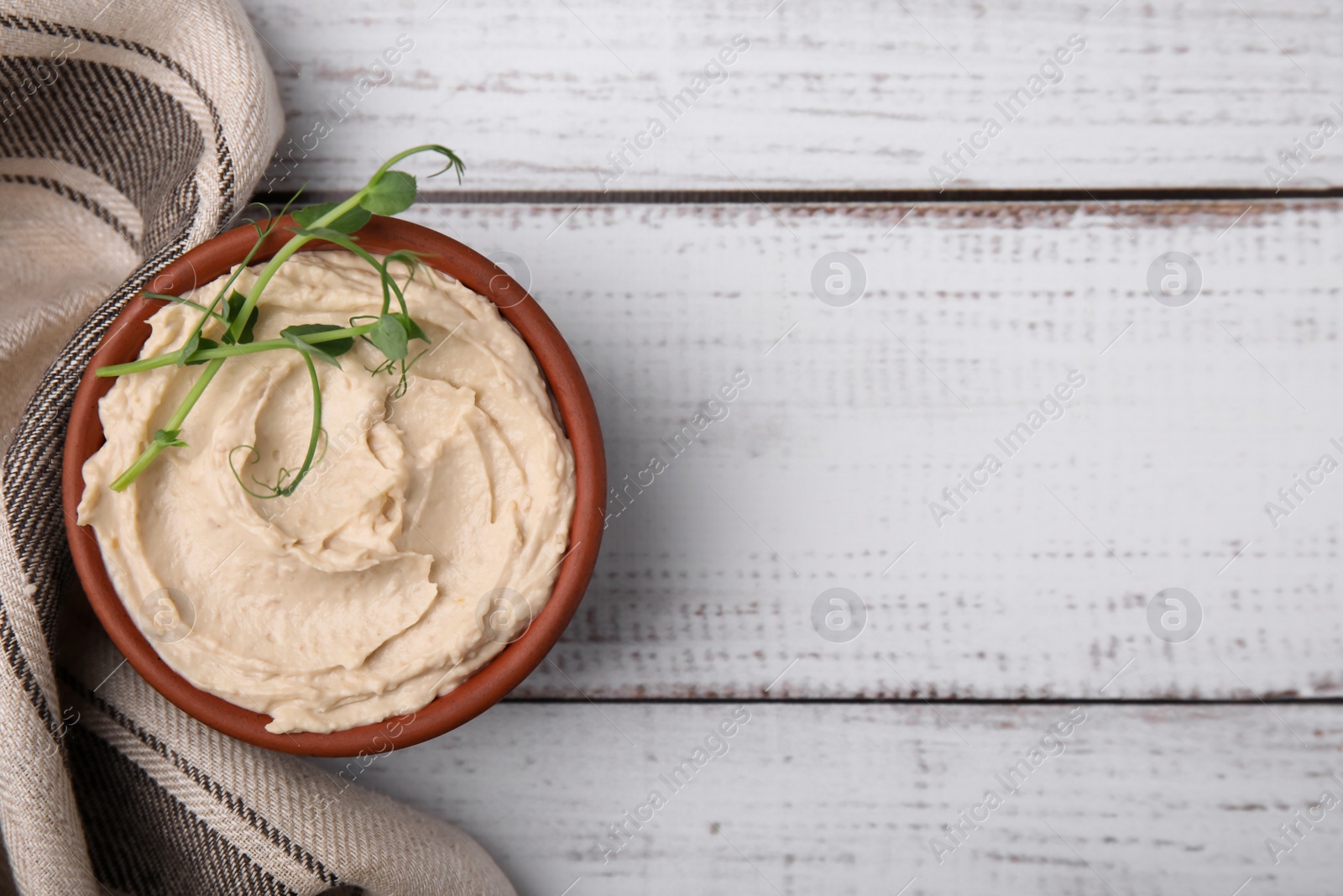 Photo of Bowl with delicious hummus on white wooden table, flat lay. Space for text