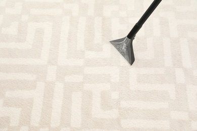 Photo of Removing dirt from carpet with vacuum cleaner indoors, closeup. Space for text