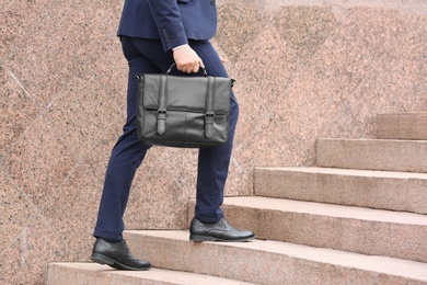 Photo of Businessman with black briefcase in hand outdoors