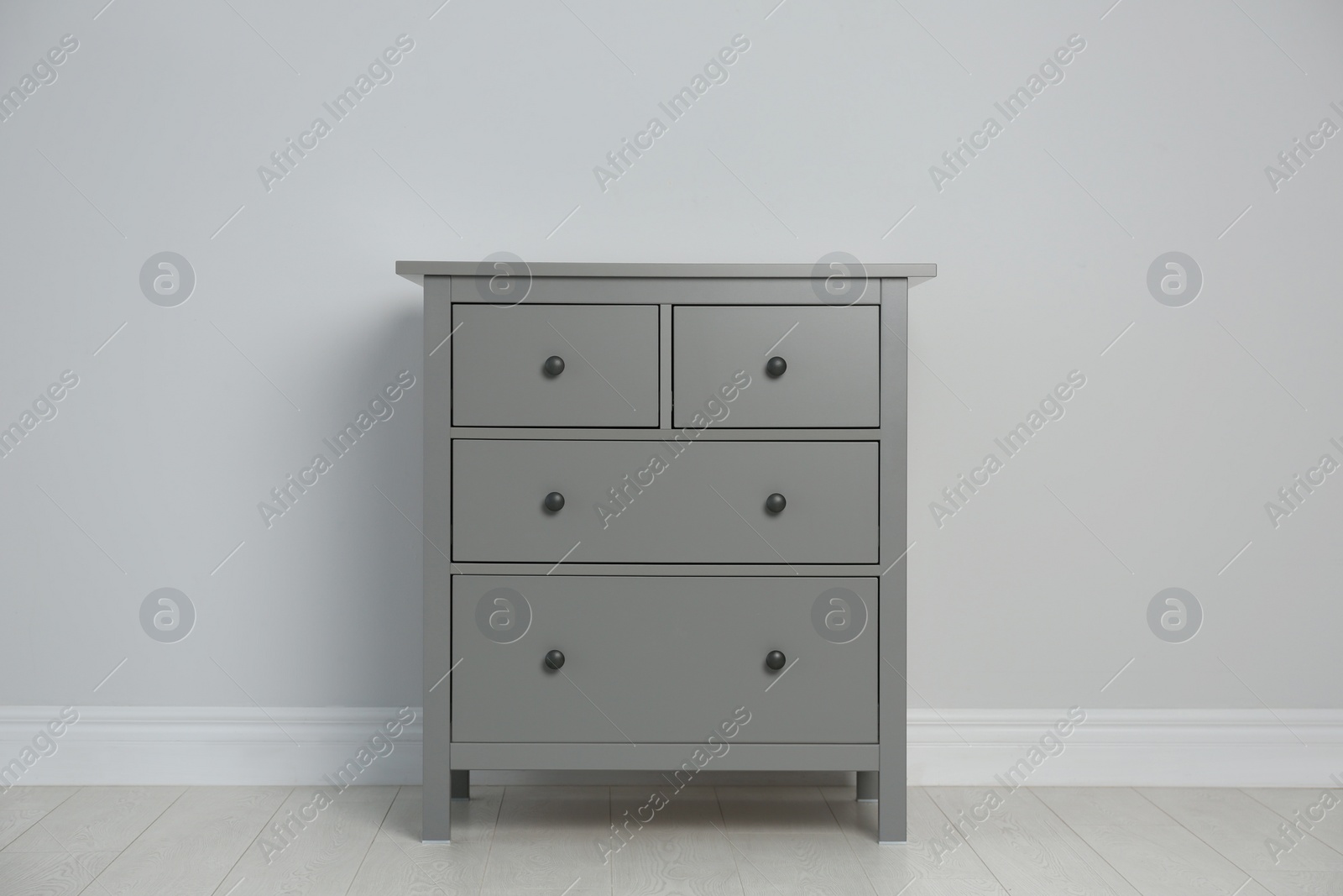 Photo of Grey chest of drawers near light wall