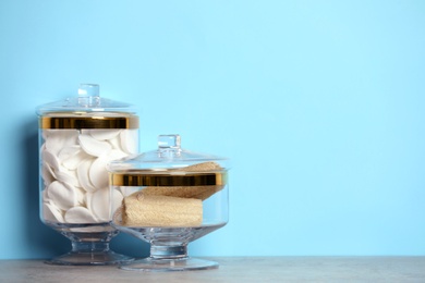 Photo of Composition of glass jar with cotton pads on table near blue wall. Space for text