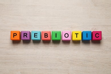 Photo of Word Prebiotic made of cubes with letters on wooden table, top view