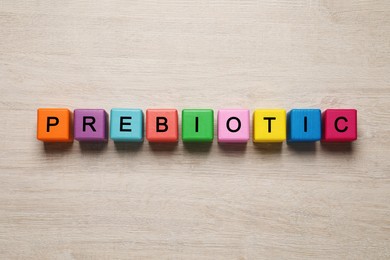 Word Prebiotic made of cubes with letters on wooden table, top view