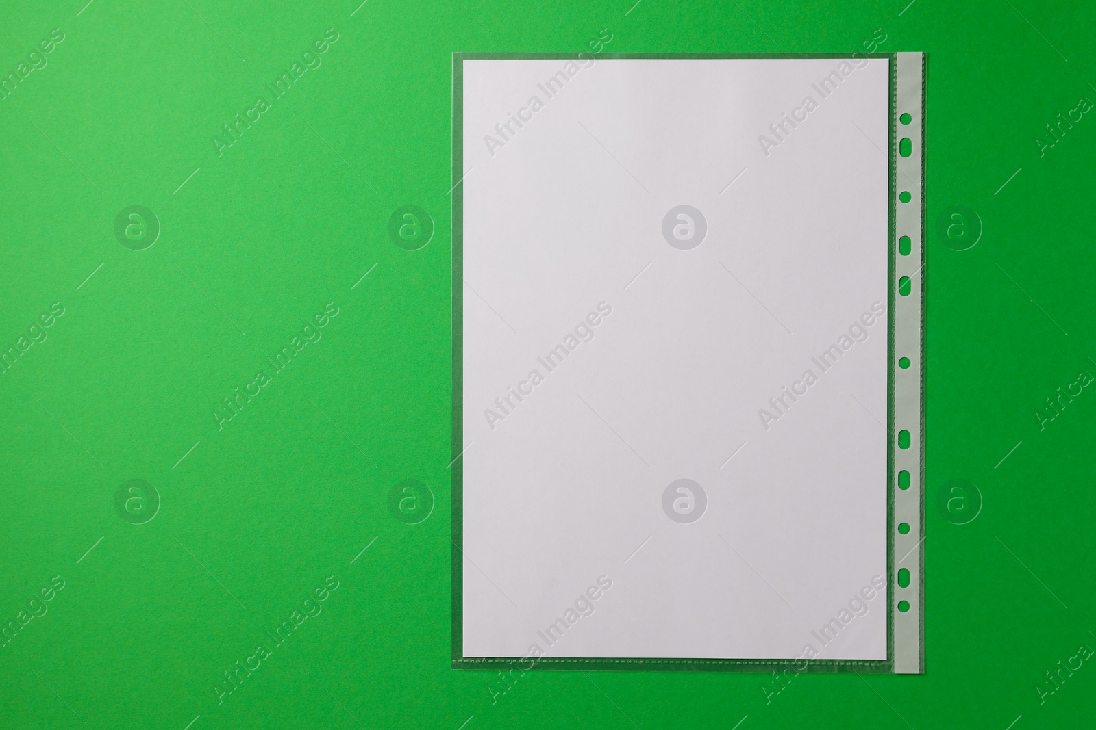 Photo of Punched pocket with paper sheet on green background, top view. Space for text