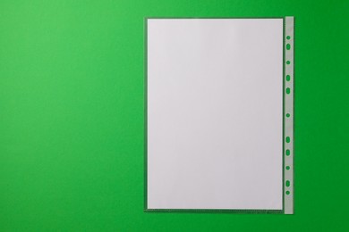 Punched pocket with paper sheet on green background, top view. Space for text