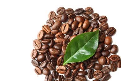 Photo of Roasted coffee beans and green leaf on white background, top view