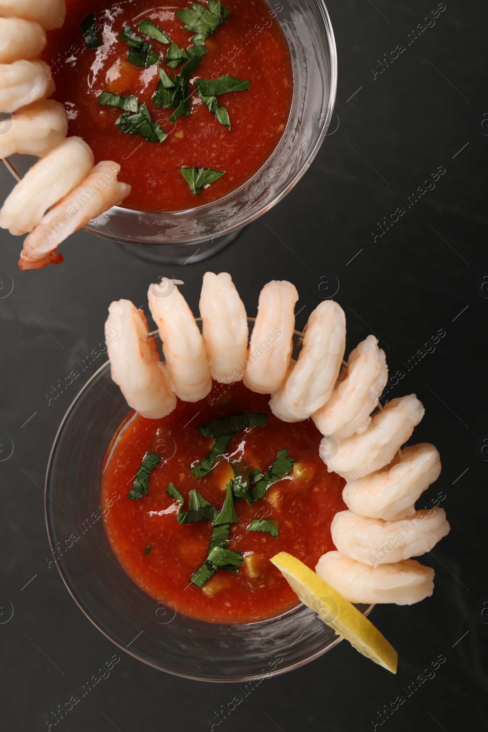 Photo of Tasty shrimp cocktail with sauce in glasses and lemon on grey table, flat lay