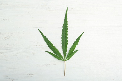 Photo of Hemp leaf on white wooden background, top view