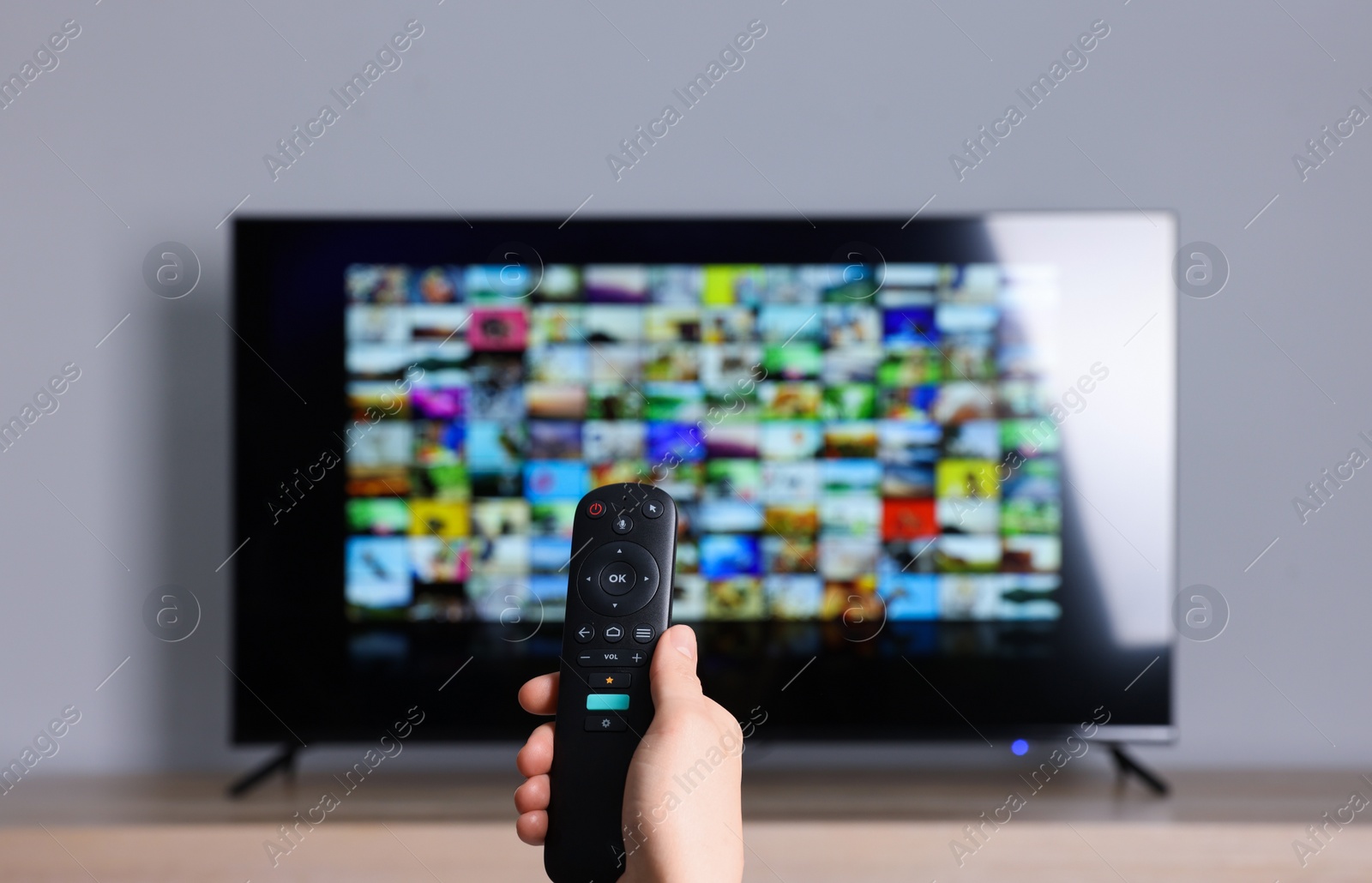 Photo of Woman switching channels on TV set with remote control at home, closeup