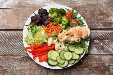 Photo of Balanced diet and healthy foods. Plate with different delicious products on wooden table, top view