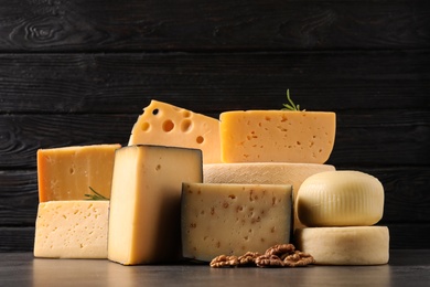 Different types of delicious cheese on table against wooden background