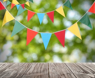 Image of Empty wooden table and decorative bunting flags outdoors
