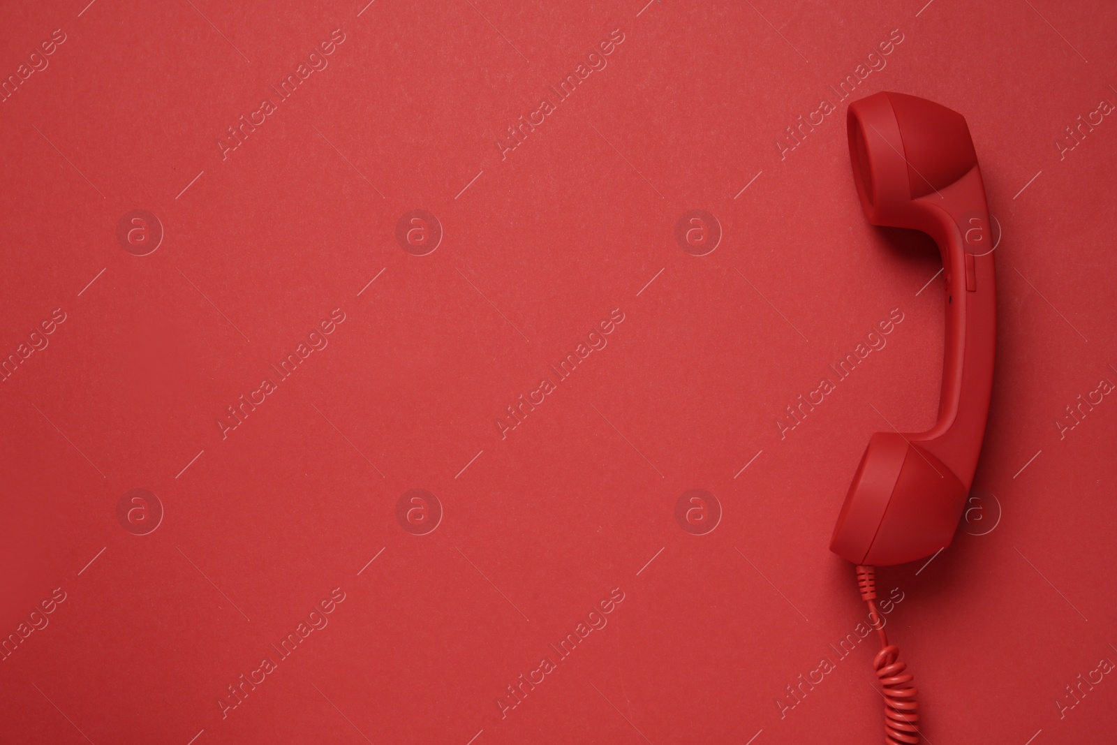 Photo of Corded telephone handset on red background, top view. Hotline concept