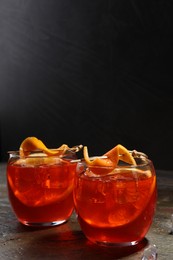Aperol spritz cocktail, ice cubes and orange slices in glasses on grey textured table, space for text