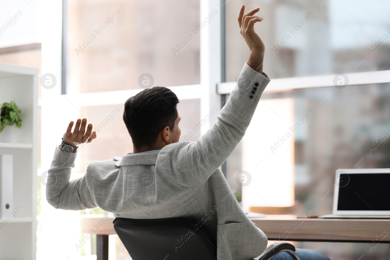 Photo of Businessman relaxing in office chair at workplace, back view. Space for text