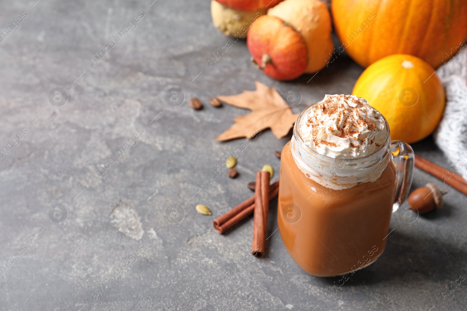 Photo of Mason jar with tasty pumpkin spice latte and space for text on gray table