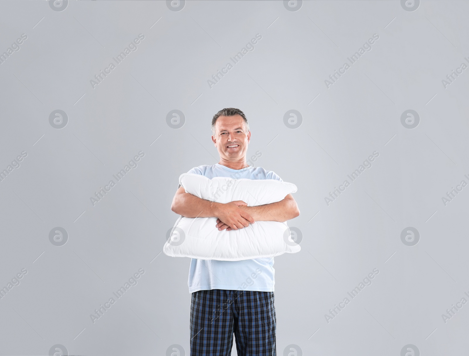 Photo of Man holding soft pillow on light background