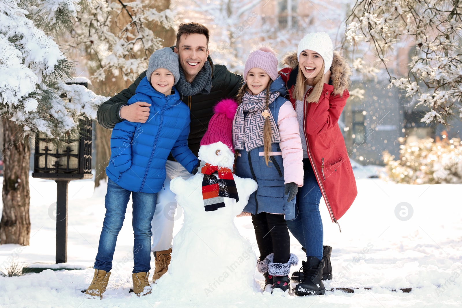 Photo of Happy family with snowman in winter park