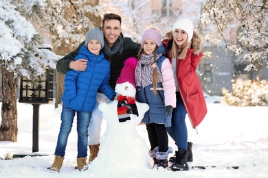 Happy family with snowman in winter park