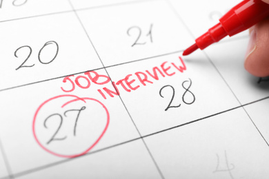 Photo of Woman marking date of job interview in calendar, closeup