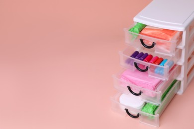 Photo of Plastic storage drawers with menstrual pads and tampons on pink background, closeup. Space for text