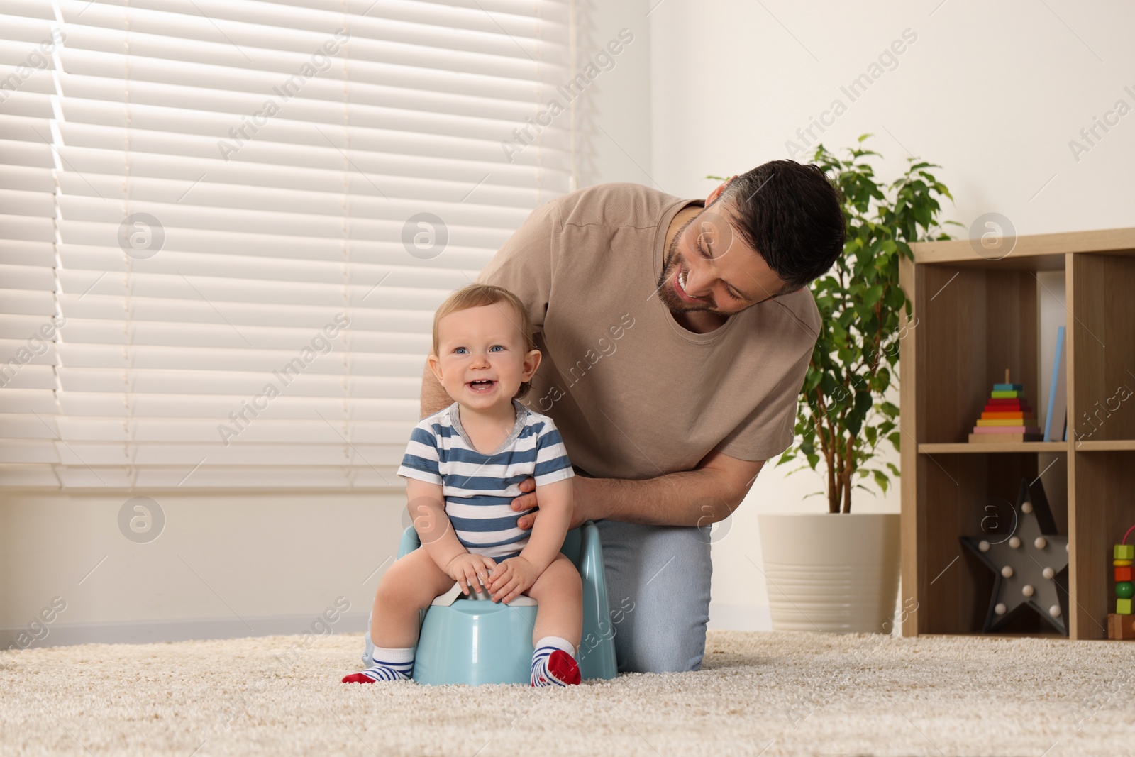 Photo of Father training his child to sit on baby potty indoors. Space for text