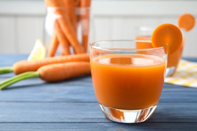 Photo of Glass with fresh carrot juice on wooden table