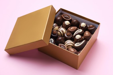 Photo of Open box of delicious chocolate candies on pink background