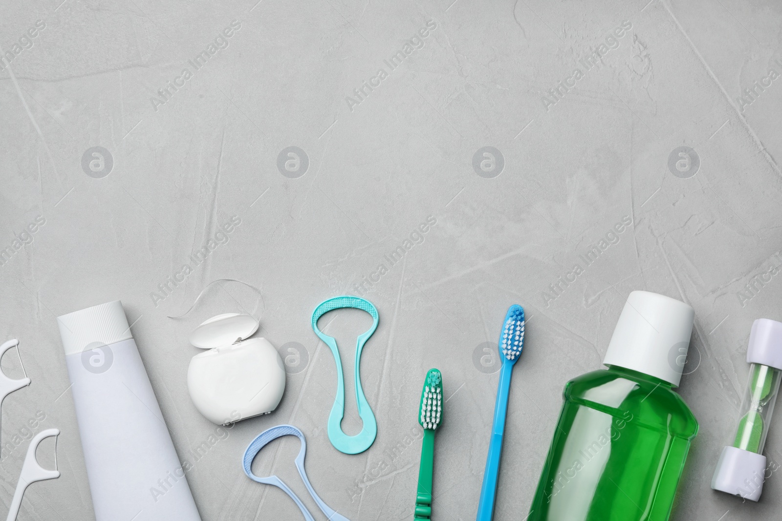 Photo of Flat lay composition with tongue cleaners and teeth care products on grey background. Space for text