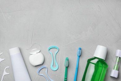 Photo of Flat lay composition with tongue cleaners and teeth care products on grey background. Space for text