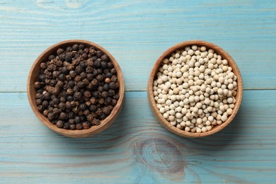 Aromatic spice. White and black peppers in bowls on light blue wooden table, top view