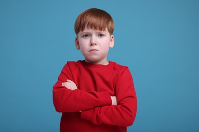 Photo of Portrait of sad little boy on light blue background