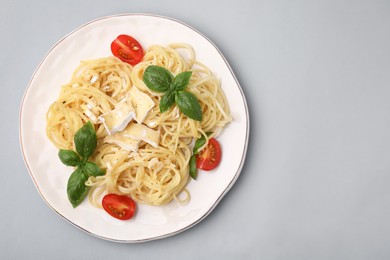 Photo of Delicious pasta with brie cheese, tomatoes and basil leaves on grey background, top view. Space for text