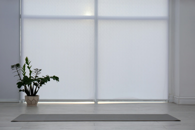 Photo of Unrolled grey yoga mat on floor in room