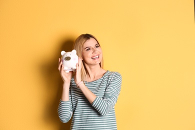 Woman with piggy bank on color background